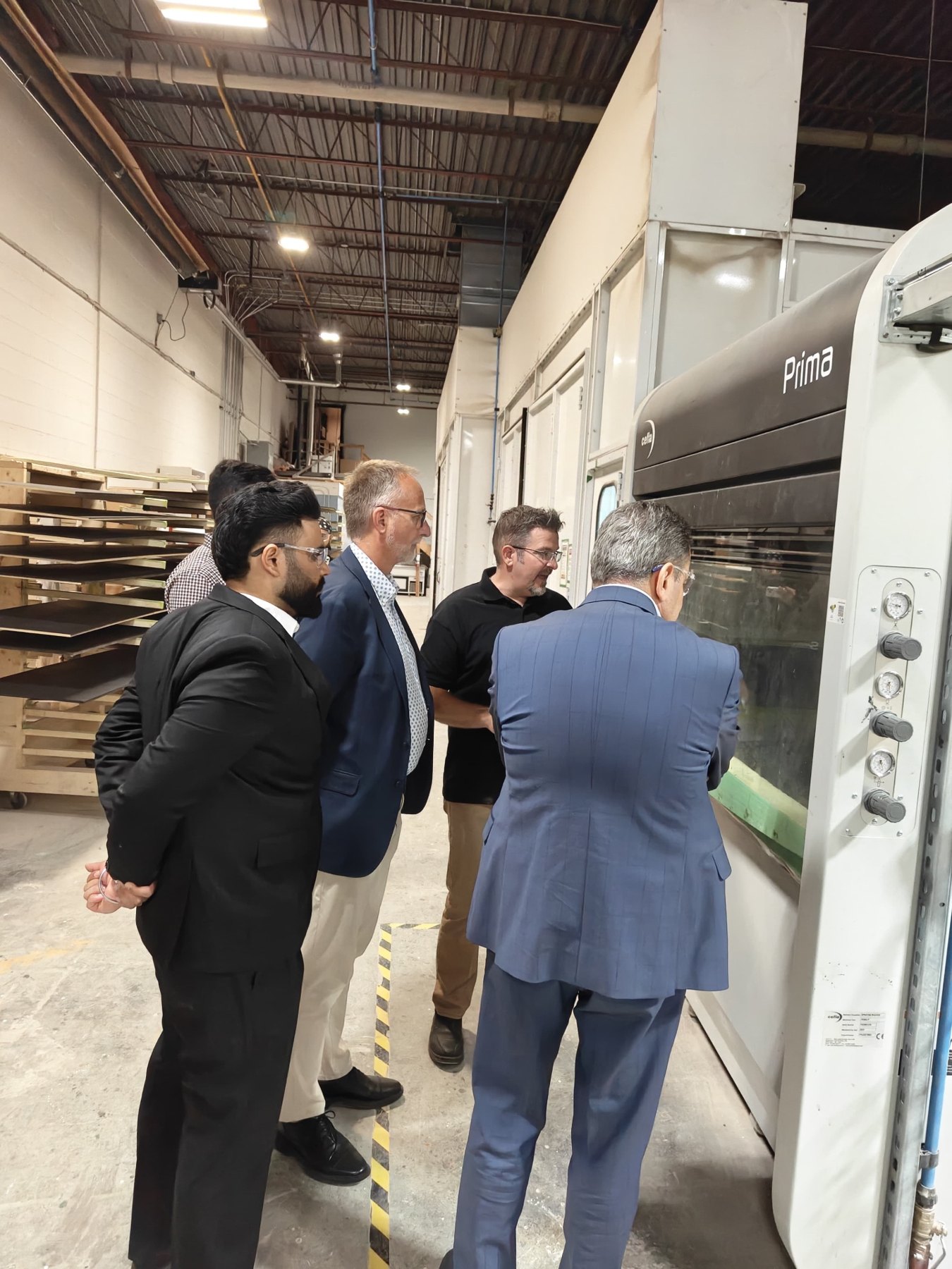 The delegation and company representatives look into an enclosed Cefla Prima finishing system.